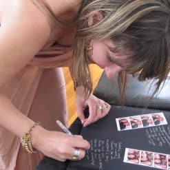 Lady Writing Inside a Dry Mount Photo Album Next To Photo Booth Strip Photos