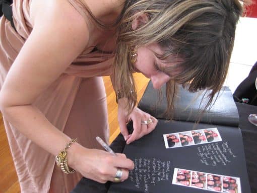 Lady Writing Inside a Dry Mount Photo Album Next To Photo Booth Strip Photos